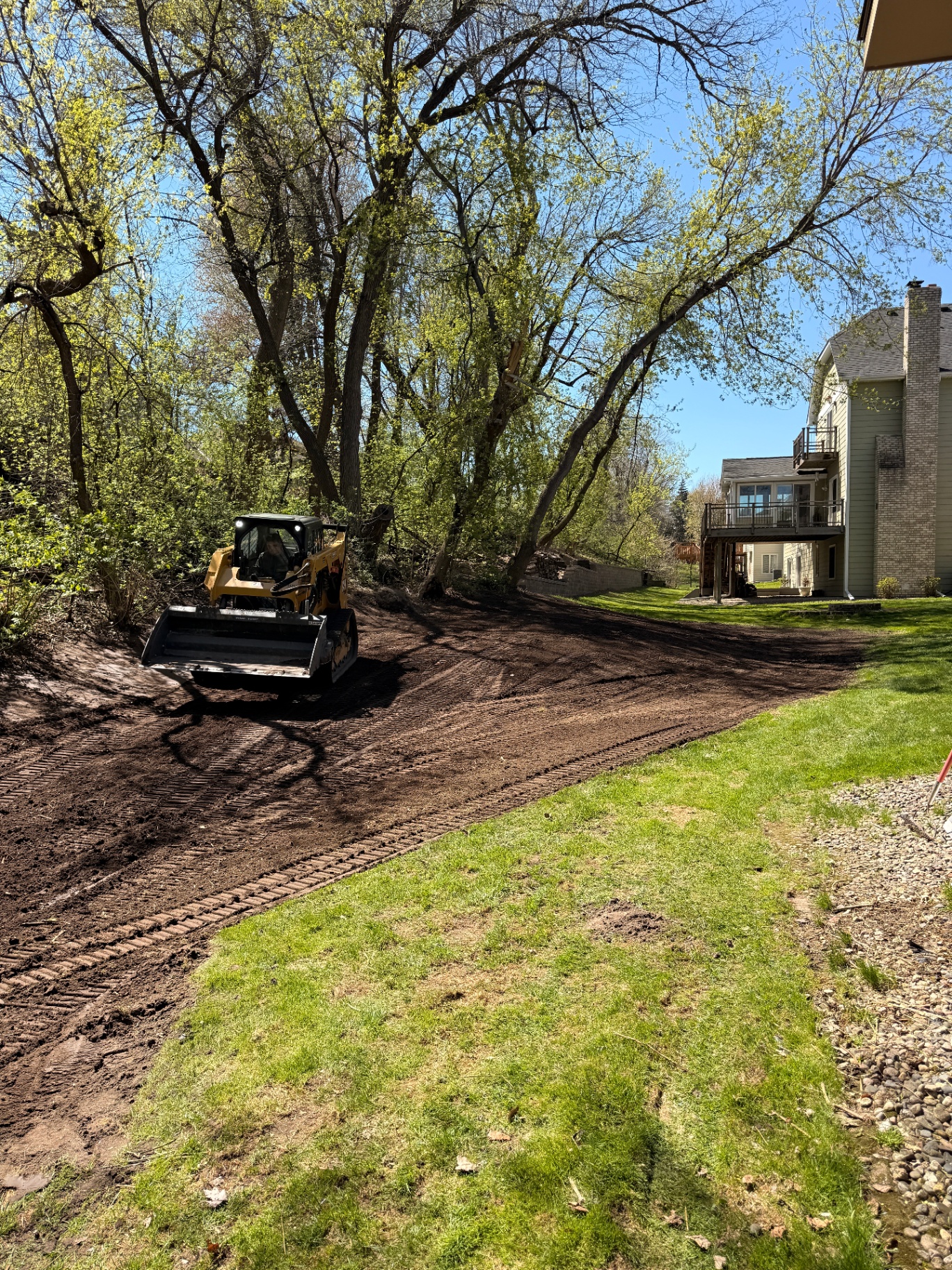 Plymouth, MN backyard renovation in progress with skid steer grading the site
